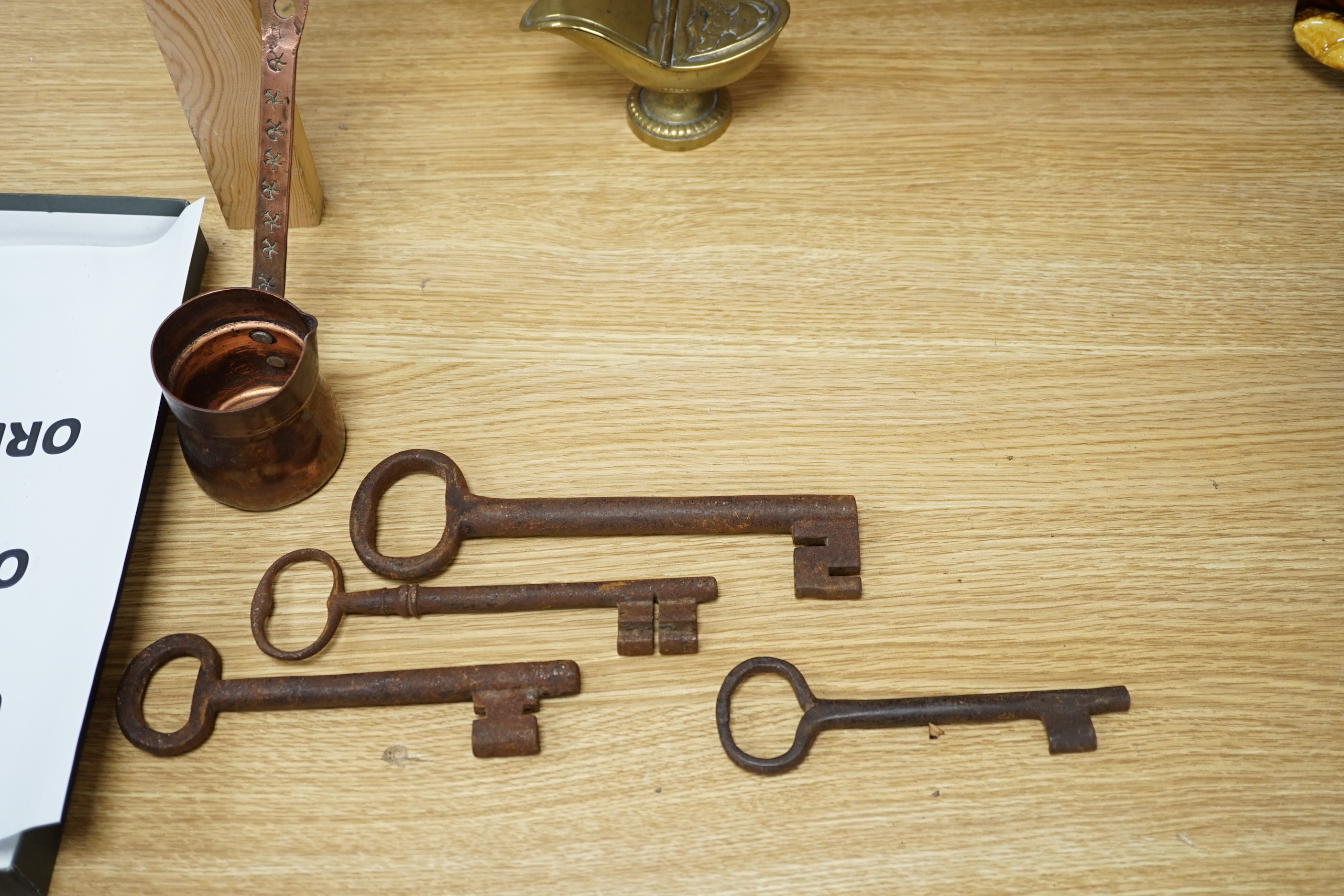 A group of mixed metalware including a pair of brass candlesticks, a brass bound book slide, iron keys, etc.